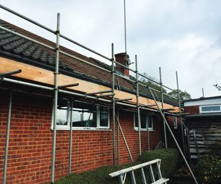 scaffolding on exterior of brick house with slate roof tiles