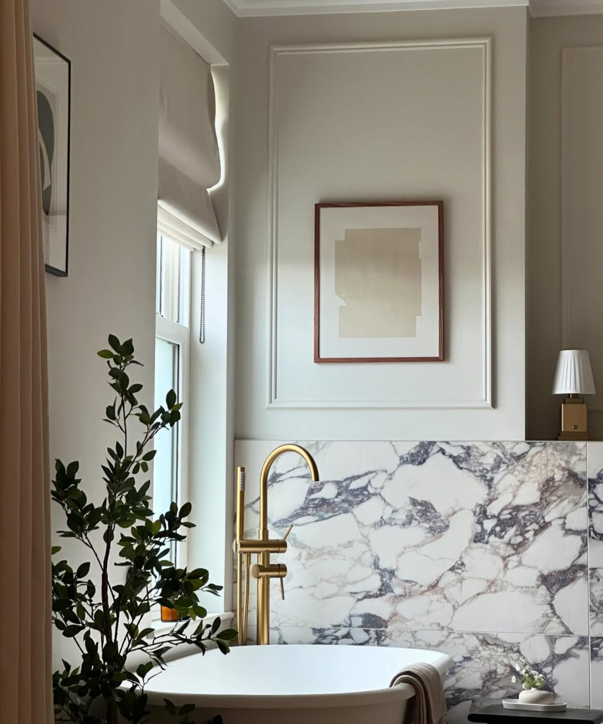 grey bathroom with half height large grey marble effect wall tiles, freestanding bath and gold taps
