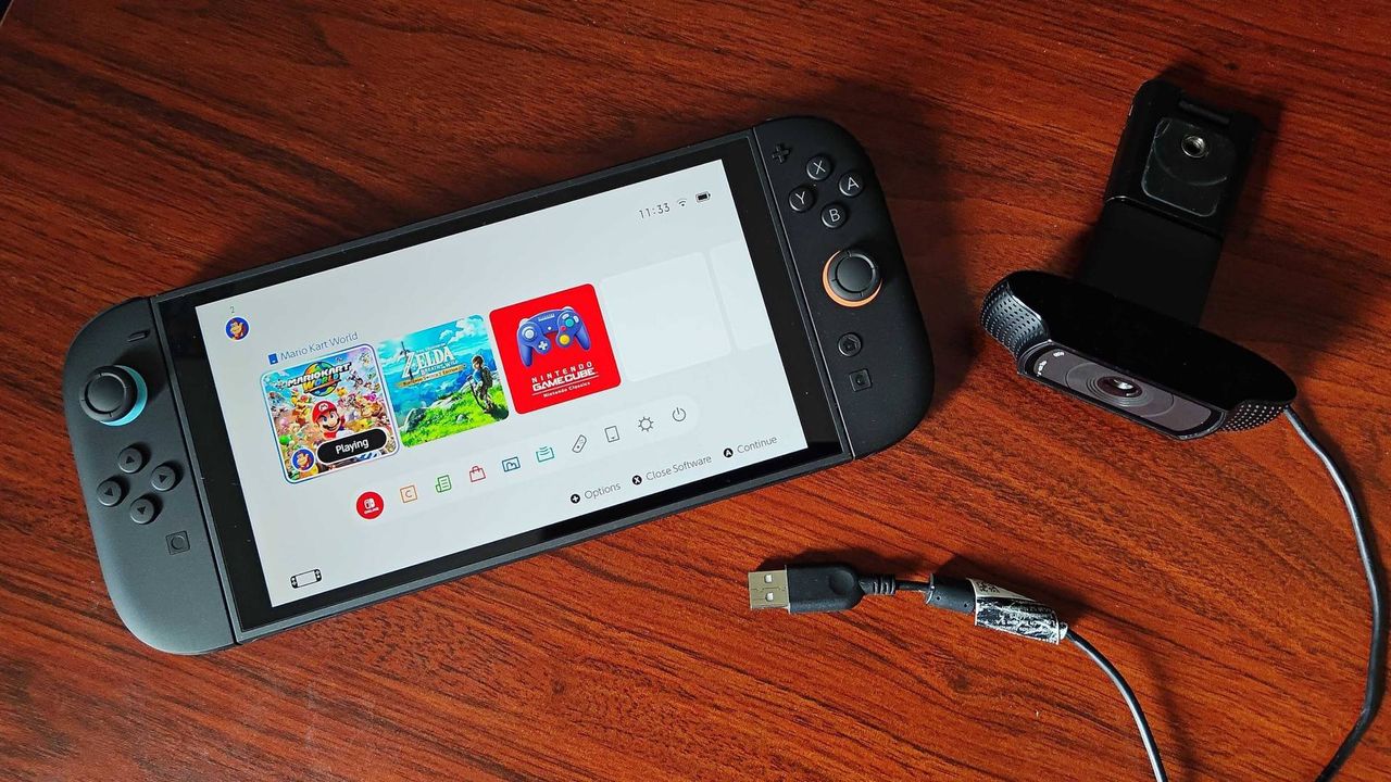 Switch 2 lying on desk next to Logitech C920 webcam.