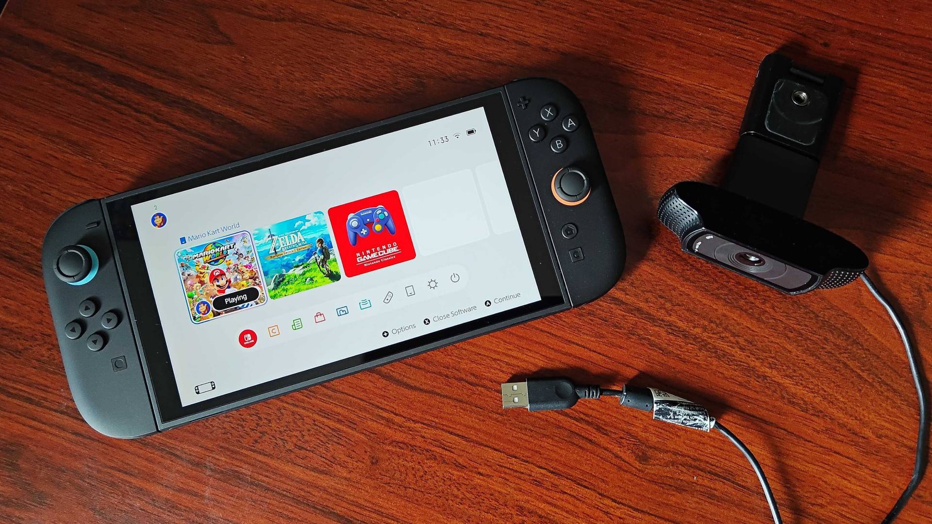 Switch 2 lying on desk next to Logitech C920 webcam.