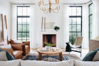 modern farmhouse style living room with fireplace, leather armchairs, gold chandelier and round timber coffee table