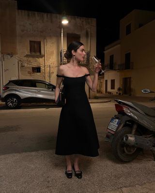 Woman wearing an elegant off-the-shoulder black dress.