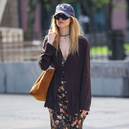 Jennifer Lawrence walks outside in New York wearing floral trousers with The Row black and red flip flops and a brown suede tote bag.