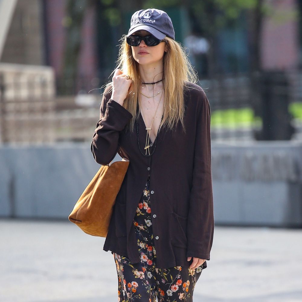 Jennifer Lawrence walks outside in New York wearing floral trousers with The Row black and red flip flops and a brown suede tote bag.