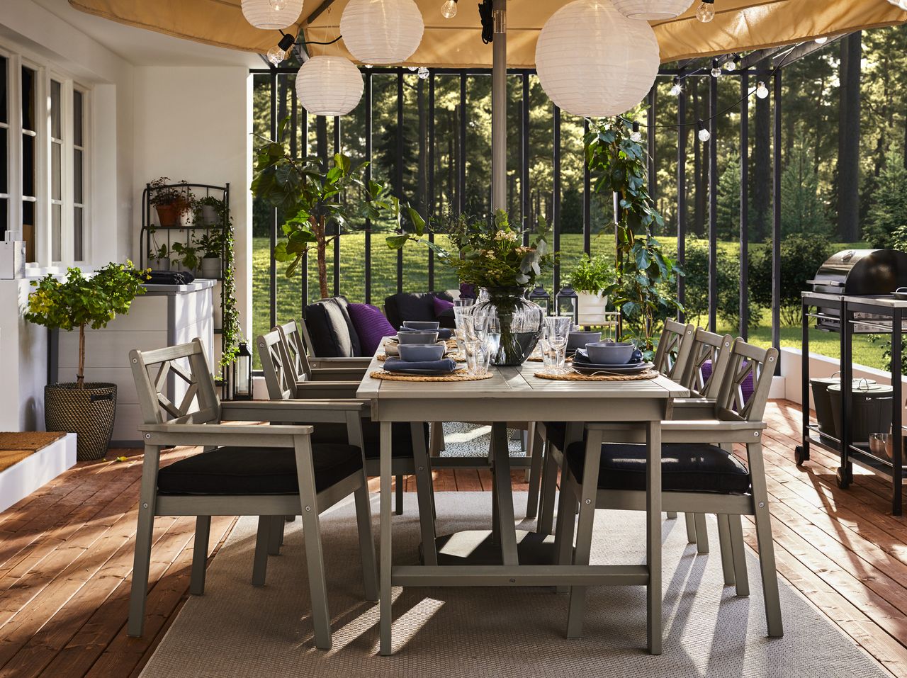 An outdoor dining area with a barbecue under a canopy with paper string light, 