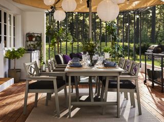 An outdoor dining area with a barbecue under a canopy with paper string light,