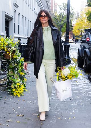 Katie Holmes wearing a leather jacket, a turtleneck, pants, and boots