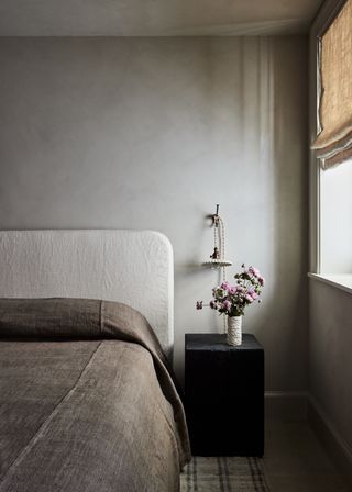 A neutral bedroom with a scalloped pendant bedside lamp and natural linen textures