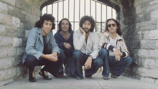 10cc crouched in front of a castle window