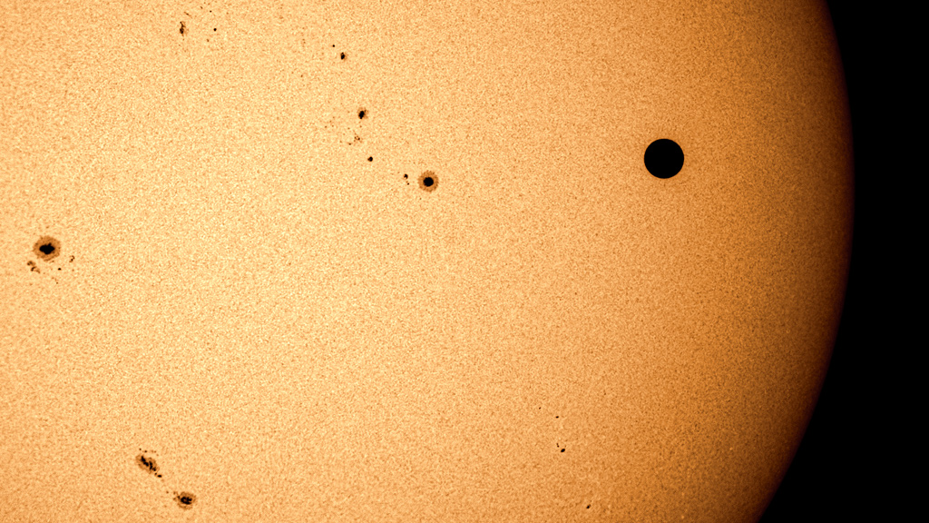 The pitch-black night side of Venus was seen in sharp relief against the solar disk using specially filtered telescopes, appearing much larger or darker than any of the numerous interesting sunspot groups visible that day. This 'white light' image also shows granulation in the sun's photosphere.