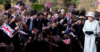 Queen Elizabeth II being greeted by schoolchildren waving flags