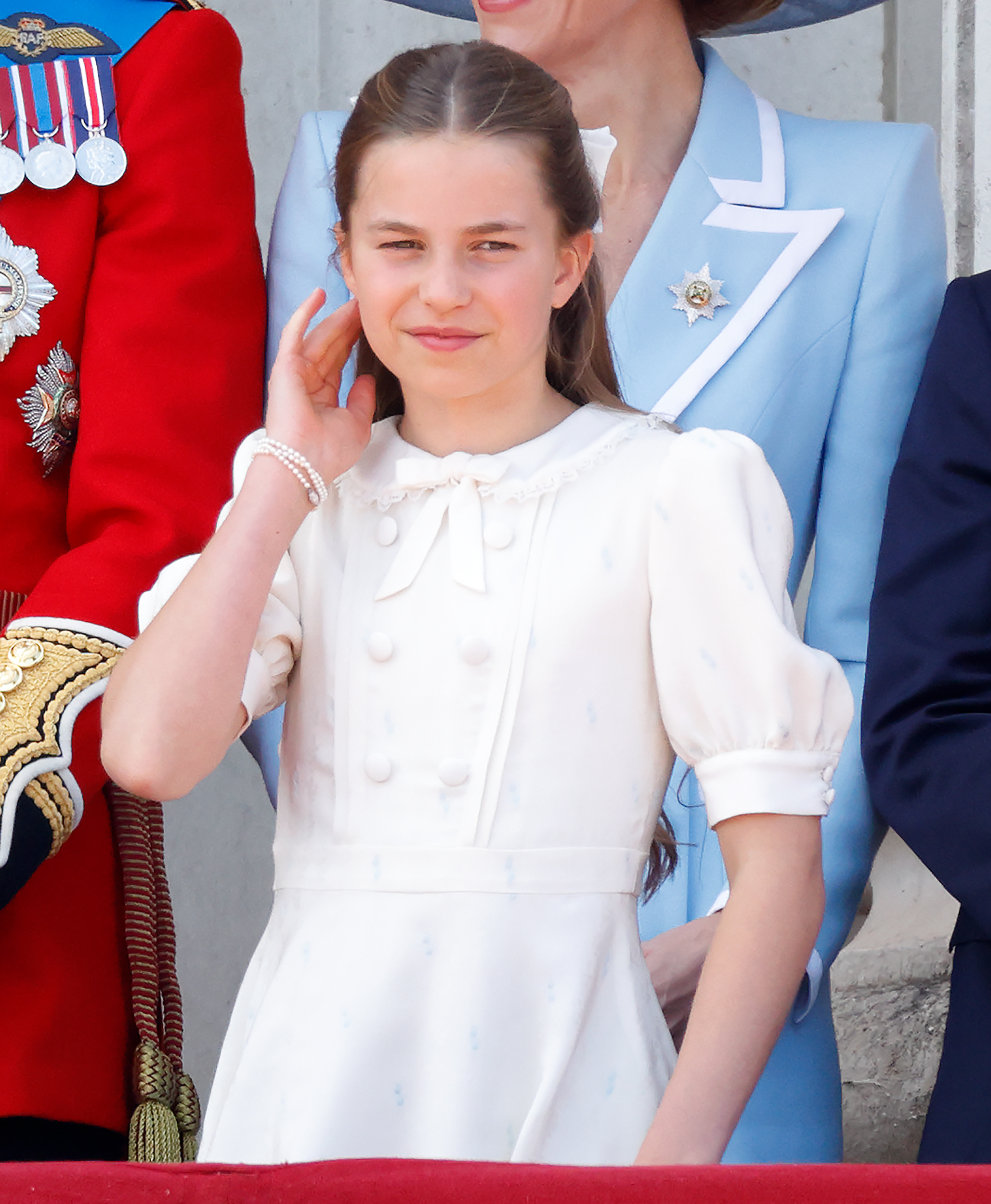 Princess Charlotte wearing a white dress with a matching bow in her long brown hair attending Trooping the Colour 2026 with the Royal Family