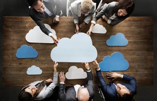 group of people stand around a table with multiple clouds around them