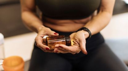 Woman putting capsules into hand at the gym, highlighting the use of creatine for women over 40