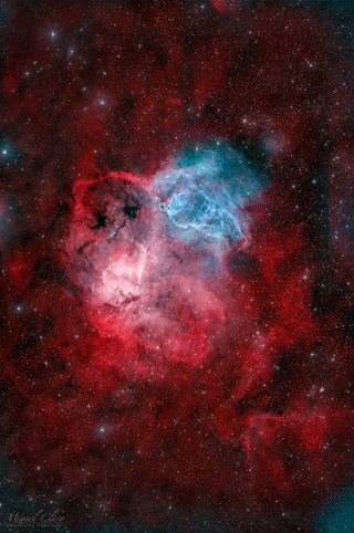 A nebula rages in space with brilliant hues of red and blue.