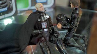 An action figure of Darth Vader lies unmasked, watched over by Luke