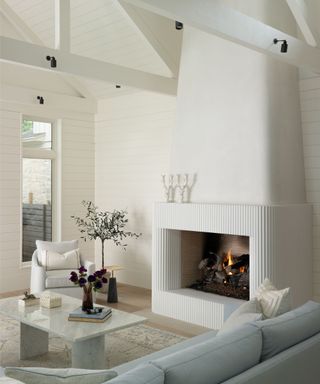 living room with fire lit with white walls and beams