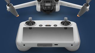 The DJI RC controller in front of the Mini 3 Pro drone on a blue background