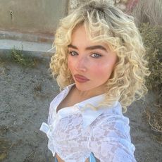 Sabrina Carpenter taking a selfie on set of her "Manchild" music video