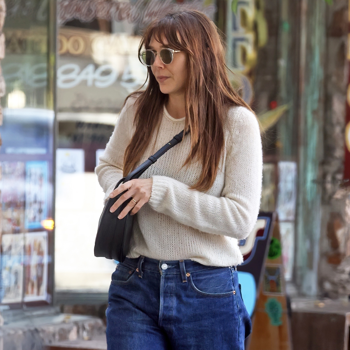 Elizabeth Olsen wearing a sweater, cropped jeans, and brown leather ankle boots