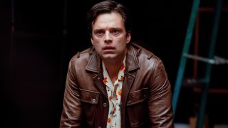 Sebastian Stan stands leaning over a table with a look of upset in A Different Man.