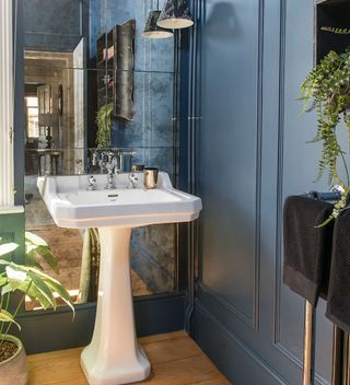 blue panelled bathroom with freestanding bath and mirrored splashback