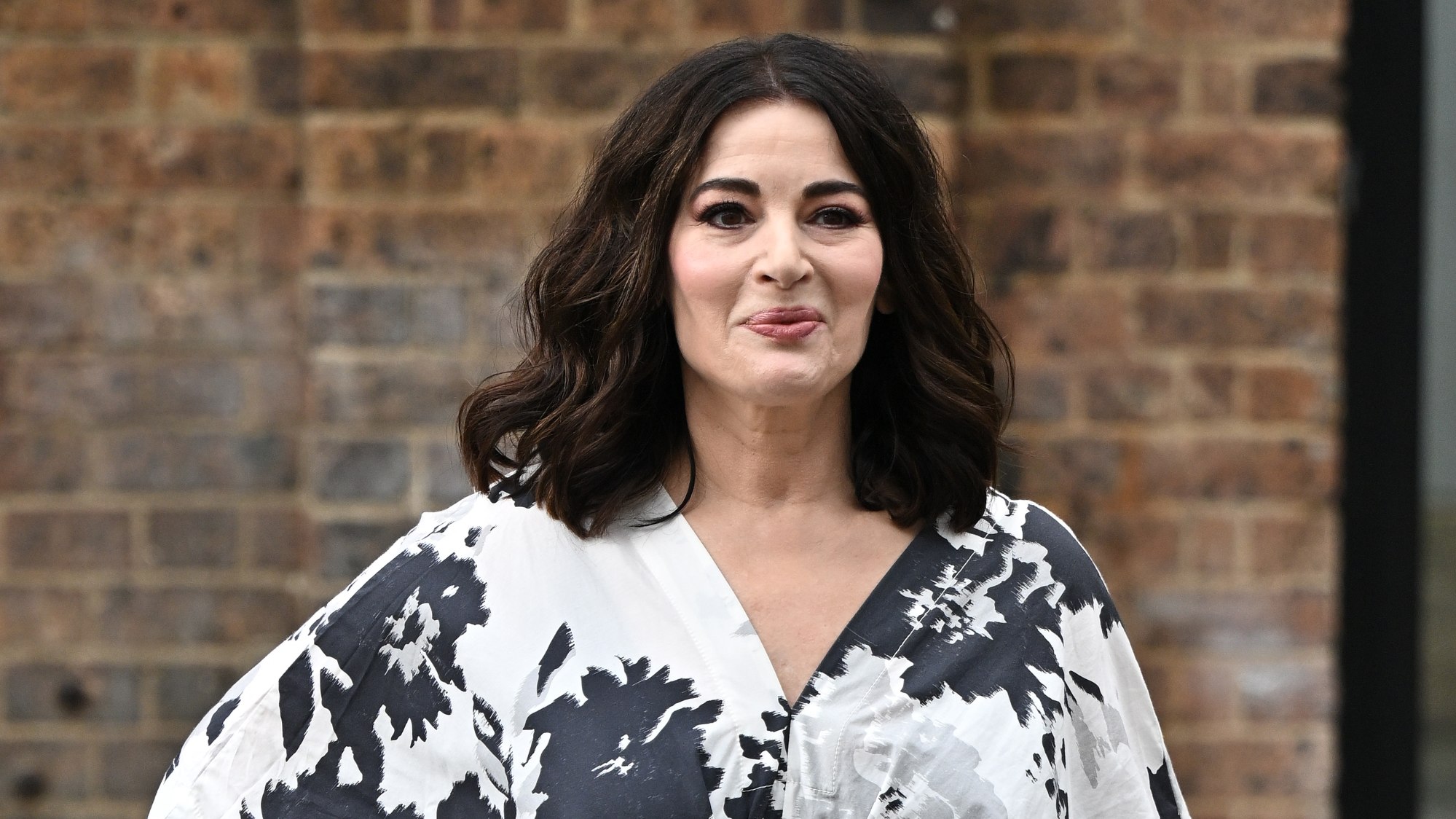 Nigella Lawson smiles, wearing a black and white floral dress, as she attends Australian Fashion Week 2025 on May 13, 2025 