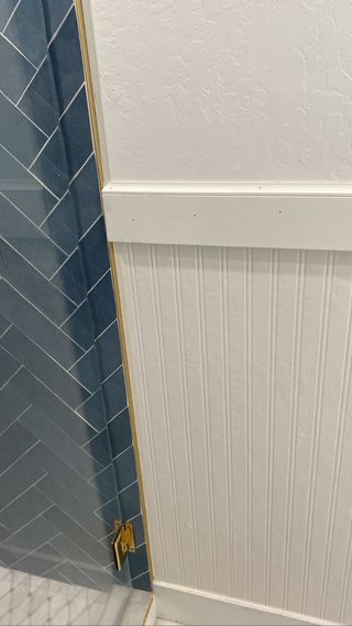 White beadboard wallpaper installed in bathroom next to blue tiled wall