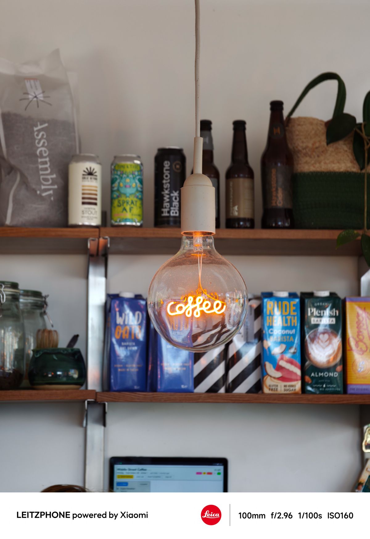 Glowing coffee light bulb hanging in front of cafe shelves
