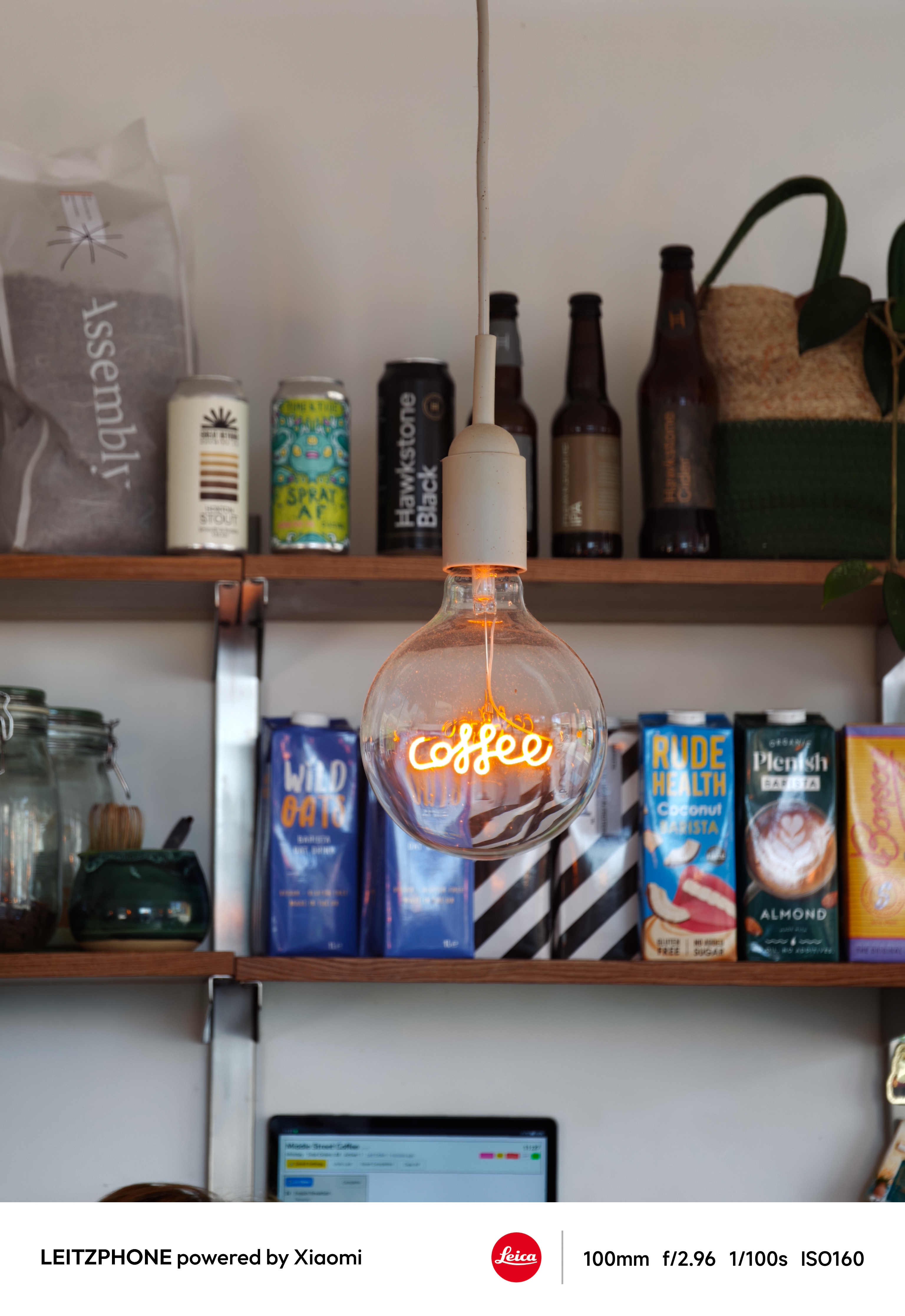 Glowing coffee light bulb hanging in front of cafe shelves
