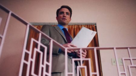 Robert Pattinson in Primetime holding papers with both hands. 