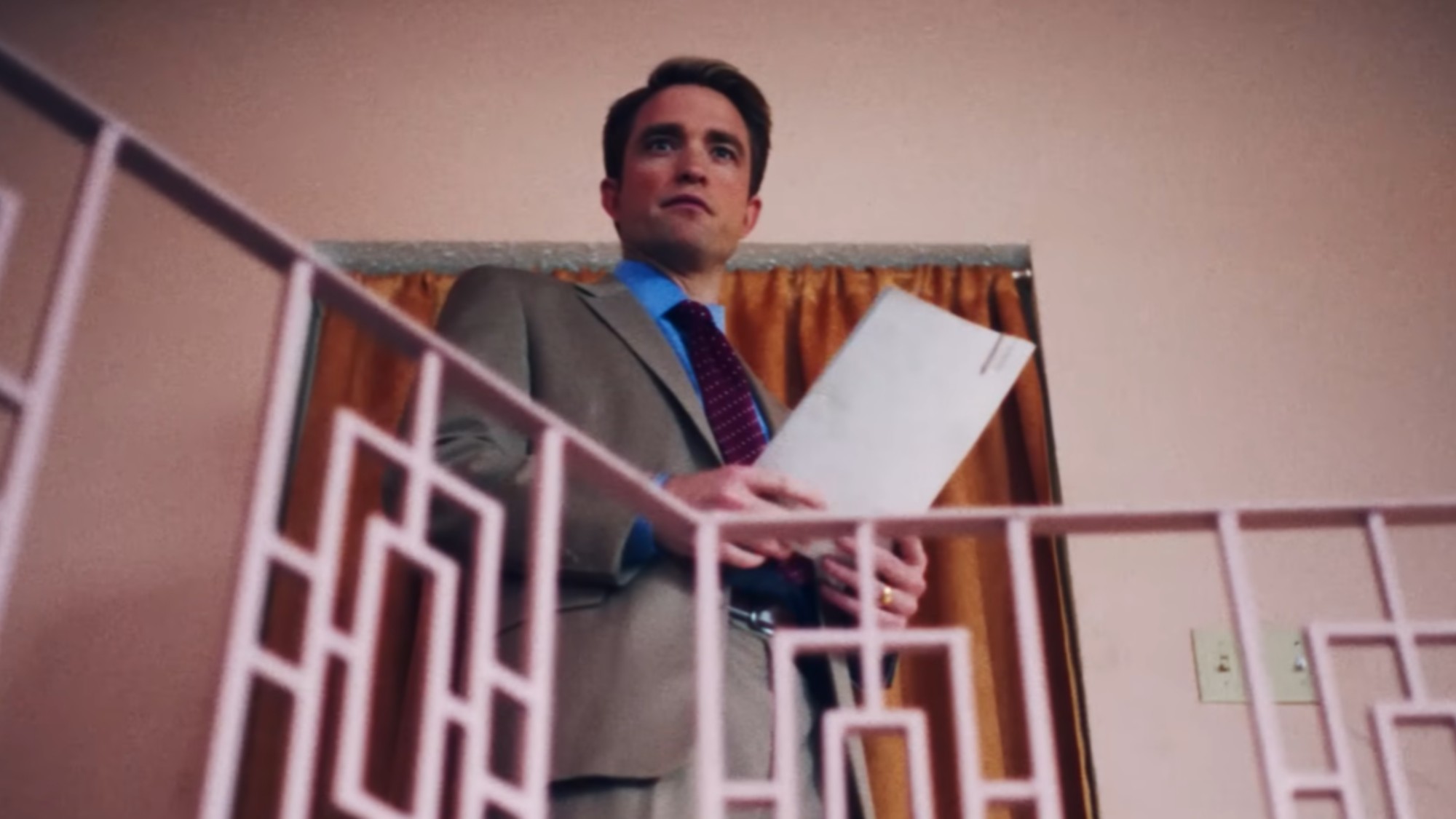 Robert Pattinson in Primetime holding papers with both hands. 