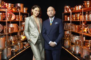 Emma Willis and Tom Allen stand in between two racks of cooking equipment