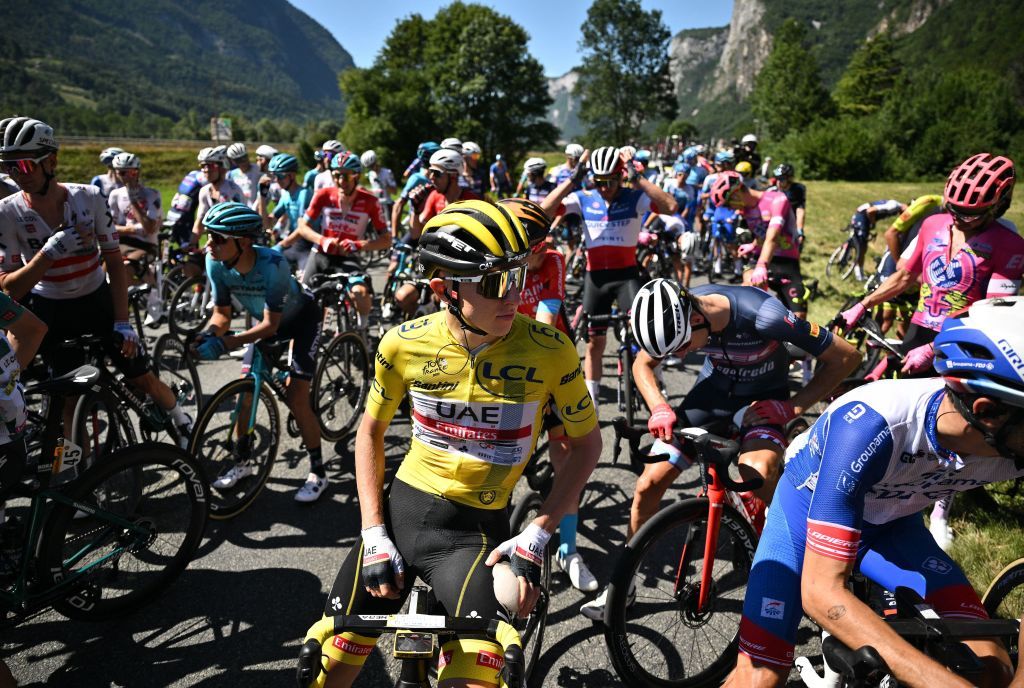 UAE Team Emirates teams Slovenian rider Tadej Pogacar C wearing the overall leaders yellow jersey and the pack of riders are temporarily immobilized by race regulators due to a demonstration by environmental protestors on the race route during the 10th stage of the 109th edition of the Tour de France cycling race 1481 km between Morzine and Megeve in the French Alps on July 12 2022 Photo by Marco BERTORELLO AFP Photo by MARCO BERTORELLOAFP via Getty Images