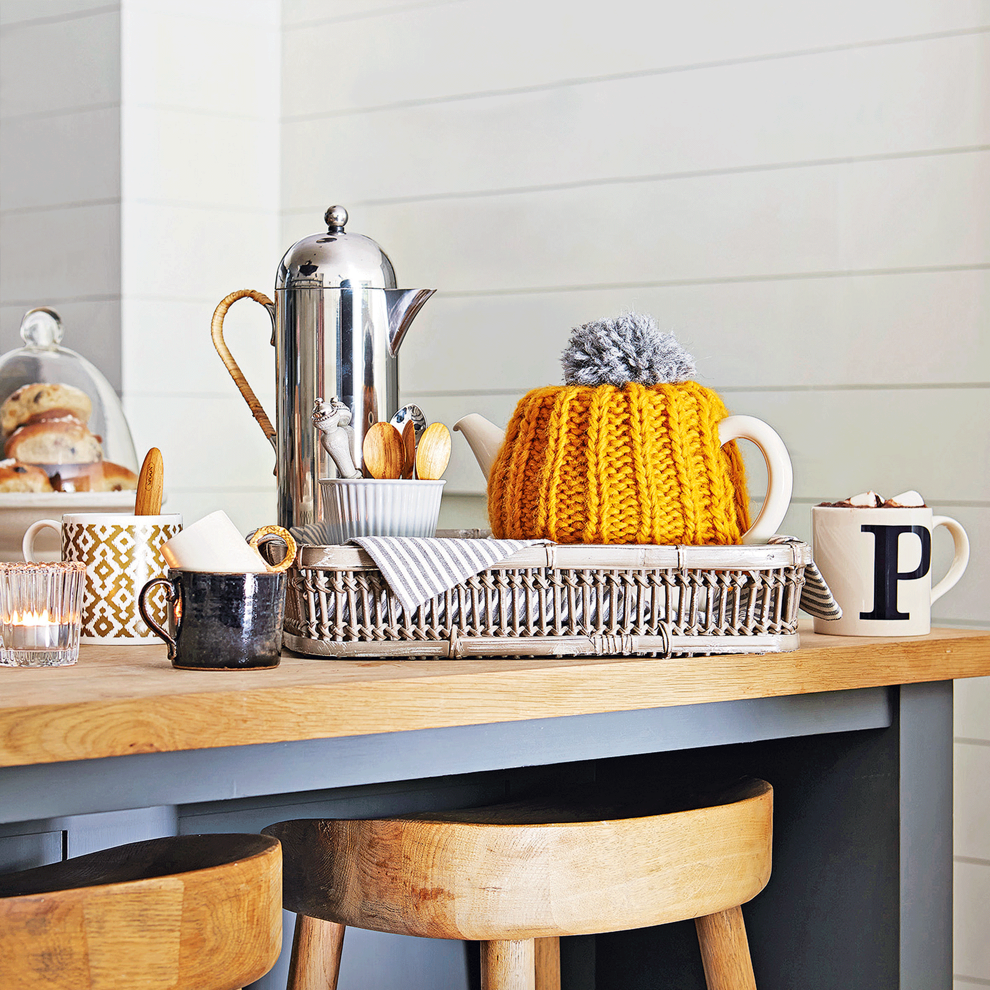 a kitchen countertop with a tray with a tea pot, coffee pot and a selection of mugs