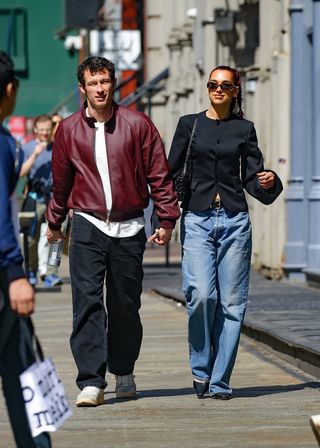 Dua Lipa wearing a black fitted jacket with jeans walking with Callum Turner in New York City