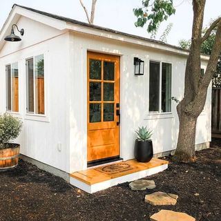 white home office shed in a backyard