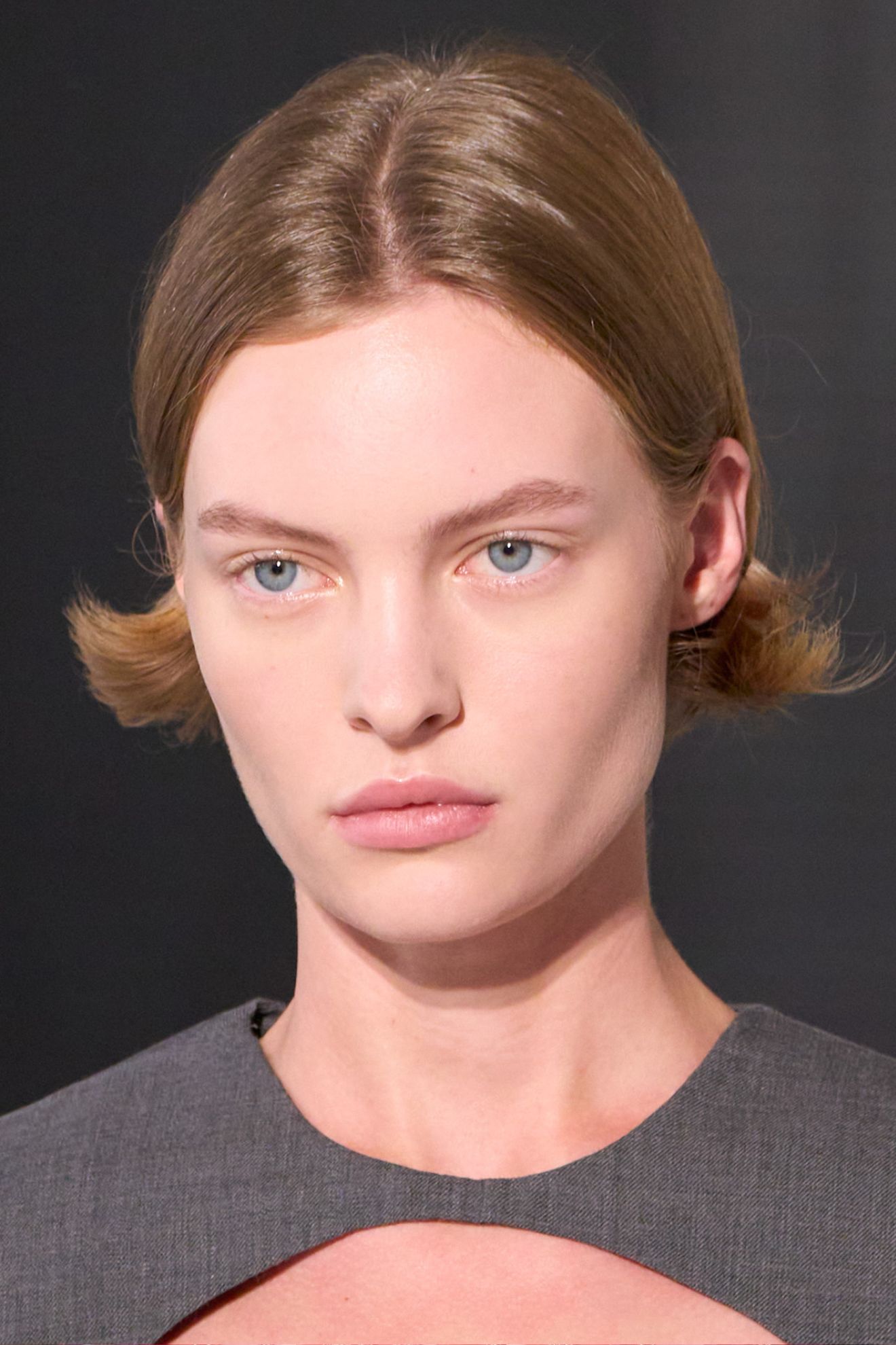 A model on the SS26 Jil Sander runway wearing a grey top with a super short, flicky bob hairstyle
