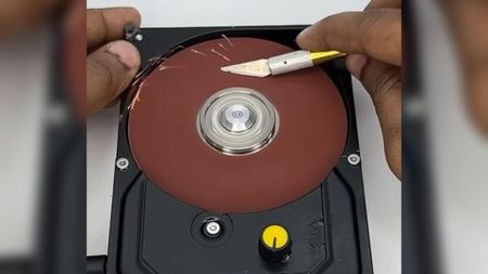 A still from a YouTube Short showing an HDD that's been converted into a disc sander, sharpening a scalpel blade