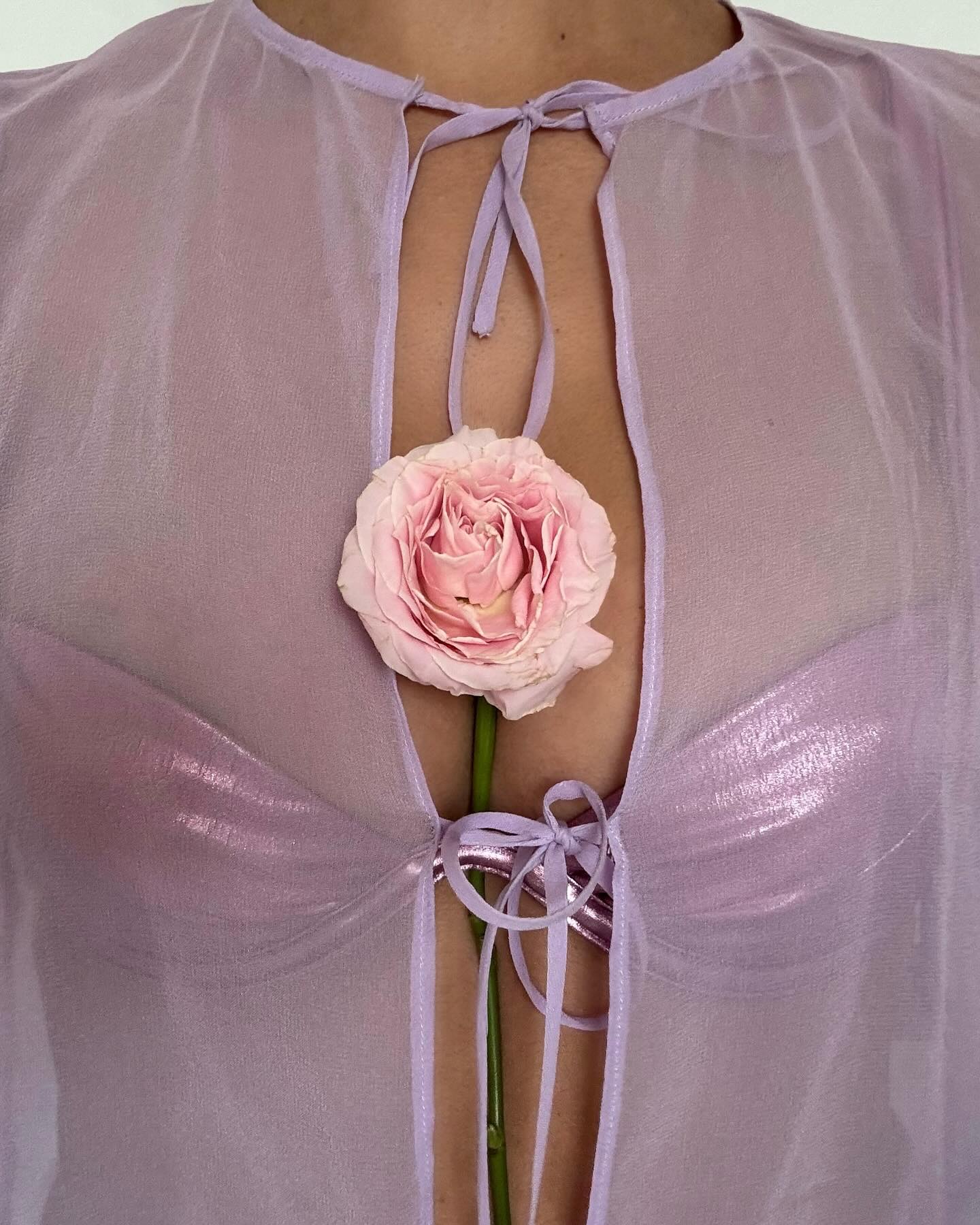 A pink flower tucked into a woman's top.