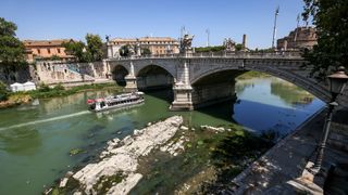 A sightseeing tourist boat sails past the resurfaced remains of an ancient bridge, which was possibly built under Roman Emperor Nero, in the Tiber River in Rome, Italy.
