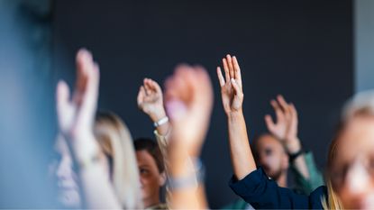 During a meeting, adults raise their hands to ask questions.