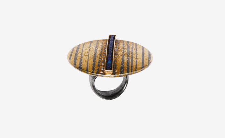 Ring with brown and orange metal disk. A channel across the middle contains blue stones