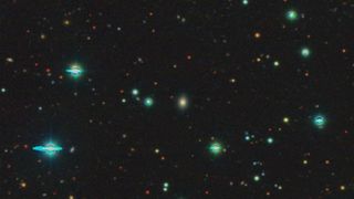 telescope image of dozens of galaxies in deep space.