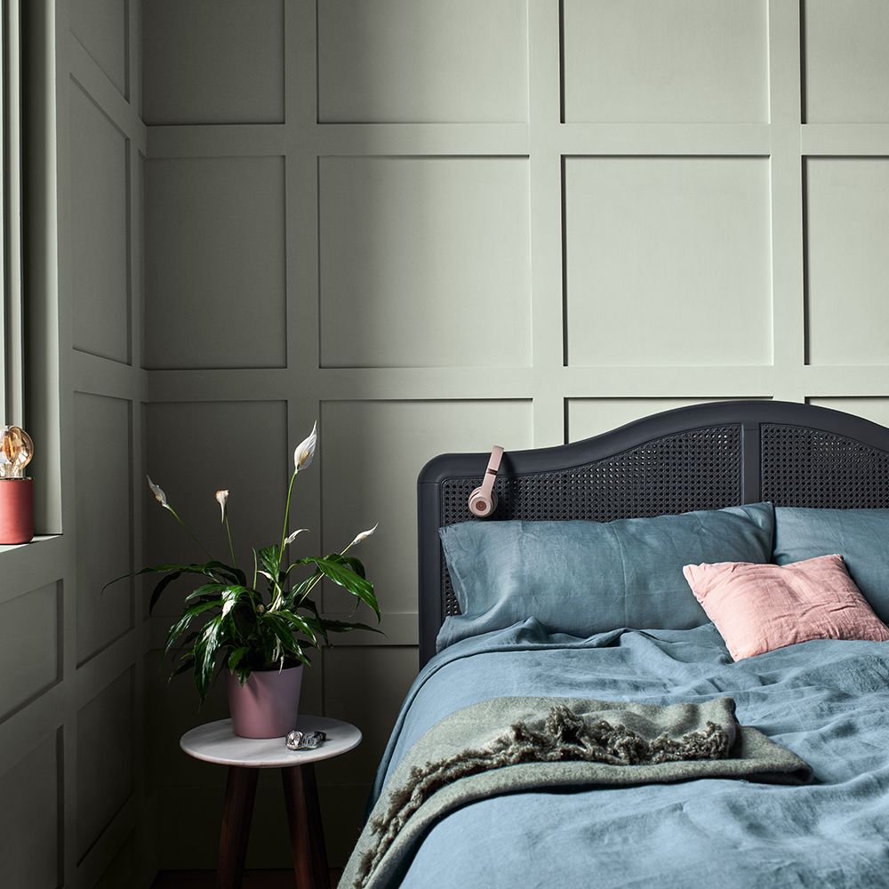 bedroom with teal wall and grey headboard and bedside table and pot