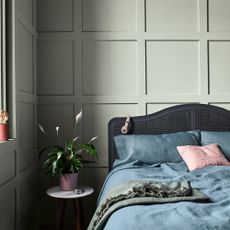 bedroom with teal wall and grey headboard and bedside table and pot 