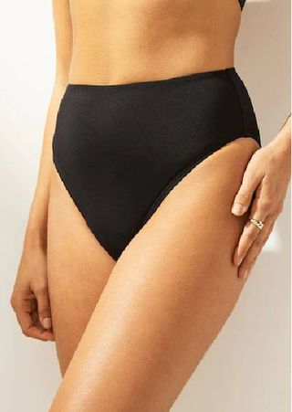 A close up of a model wearing high waisted black bikini bottoms from Next.