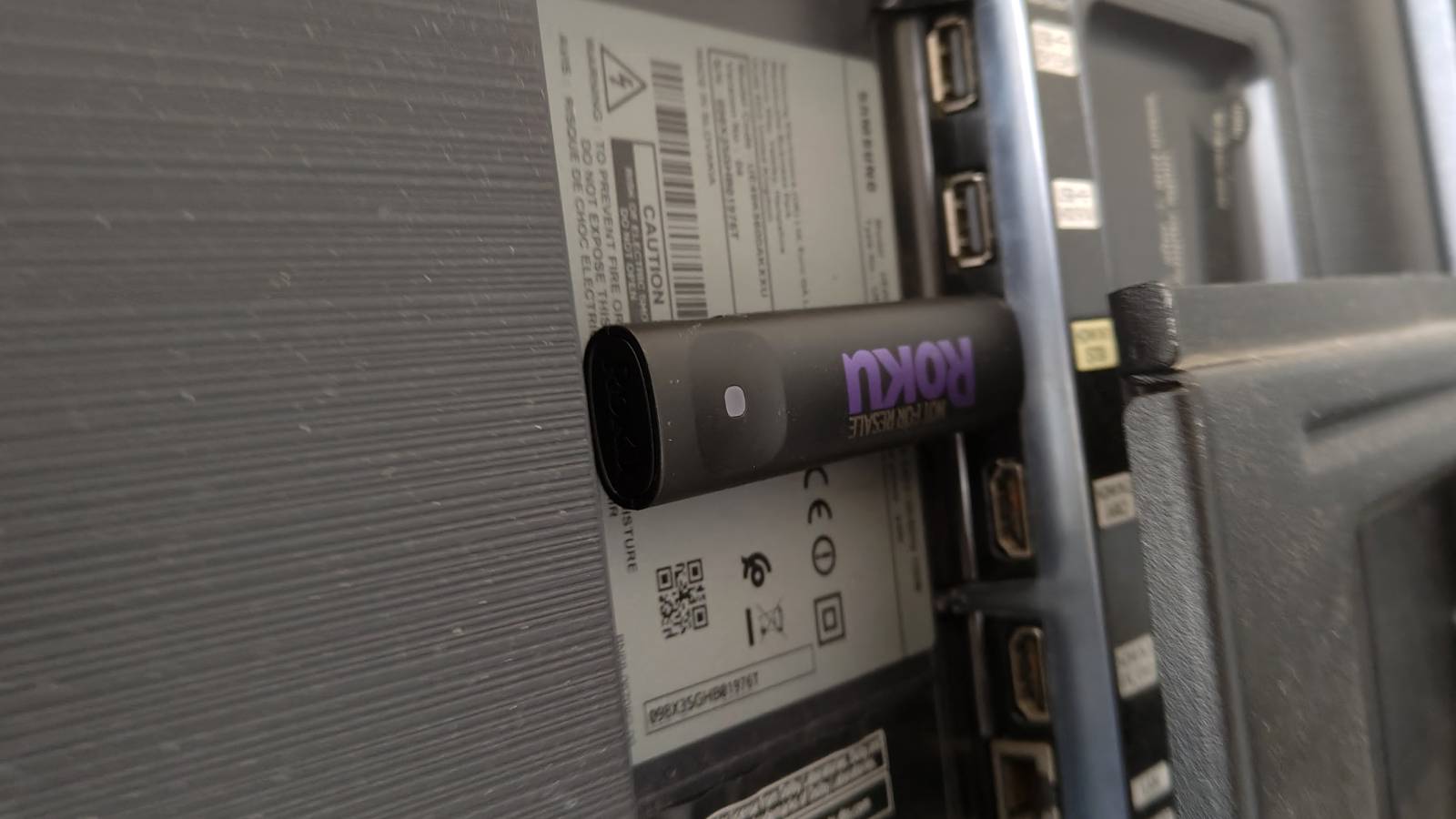 The Roku Streaming Stick partially plugged into the back of a TV.