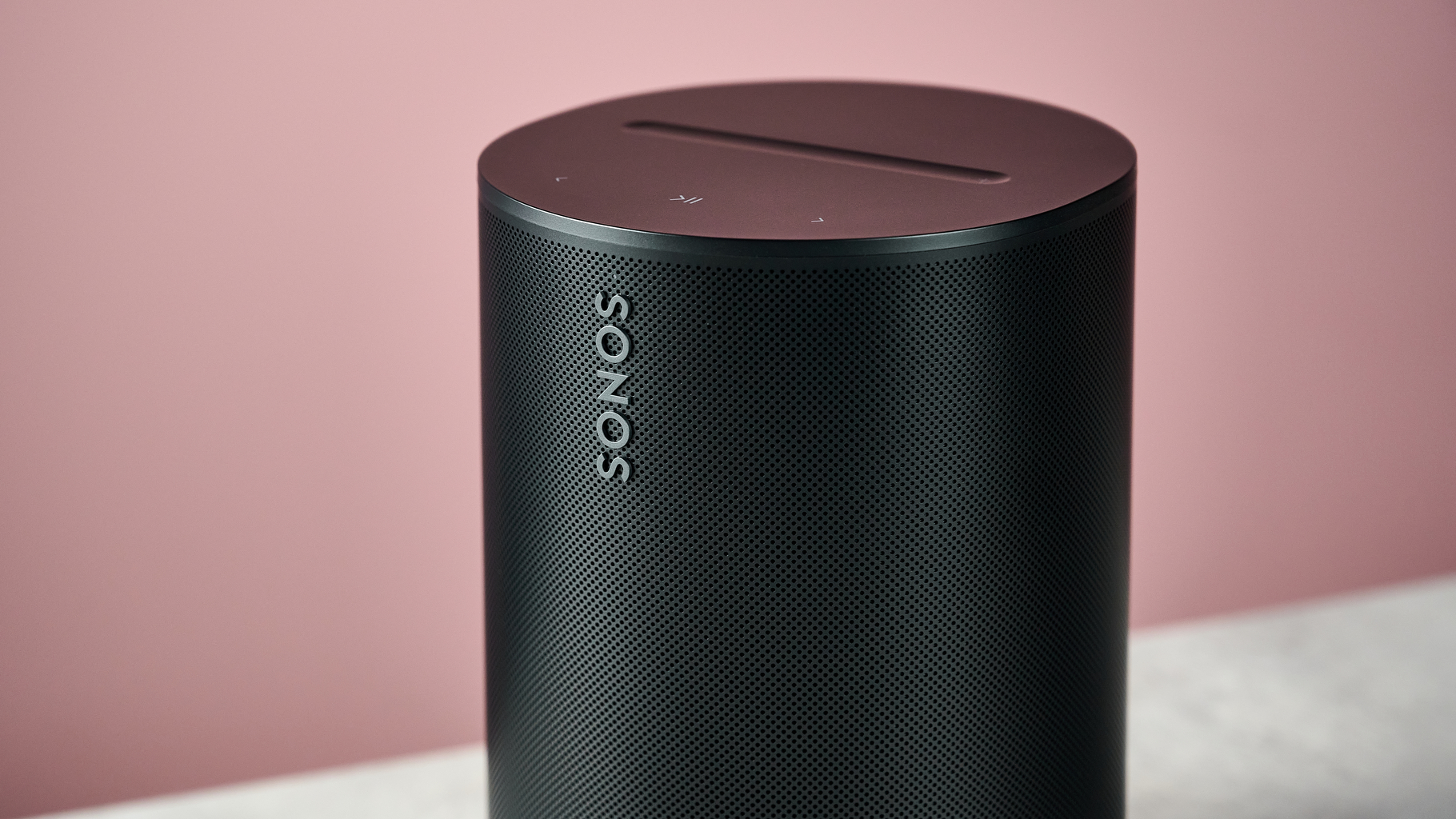 A closeup of the Sonos Era 100 SL, showing the Sonos logo on the front and the buttons on top.