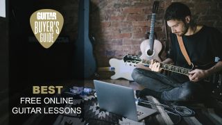 Man sat on the floor plays electric guitar in front of his laptop